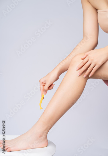 Young Asian girl is using a razor to shave her legs