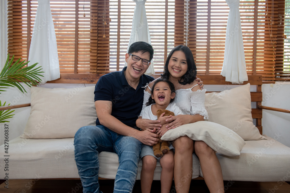 Happy Asian family parents with child girl kid spending time together relax and having fun at home. Smiling father and mother with little daughter sit on sofa together in living room with happiness. Happy Asian family parents with child girl kid spending time together relax and having fun at home. Smiling father and mother with little daughter sit on sofa together in living room with happiness.