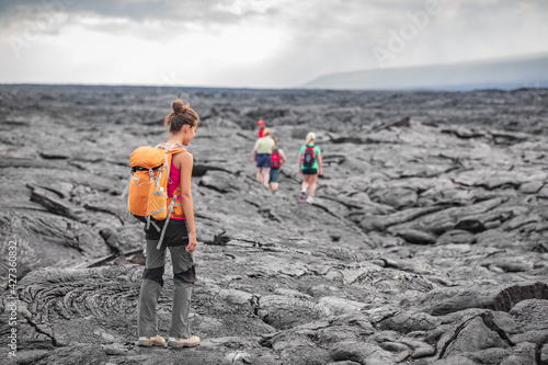 Foto Hiking group of hikers walking on Hawaii volcano lava field hike adventure happy woman with backpack in Big Island, Hawaii