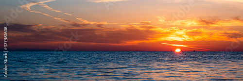 Beautiful sunset on the sea coast. The sun reflecting on the sea. Nature background. Banner.