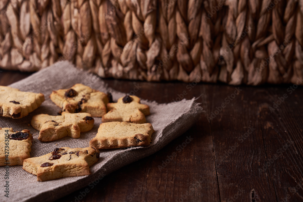 Fototapeta premium Healthy homemade gluten-free, lactose-free cookies of various shapes without sugar with raisins and chocolate on a dark brown wooden background