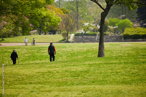 春の新緑の公園で散歩している人々の姿 © zheng qiang