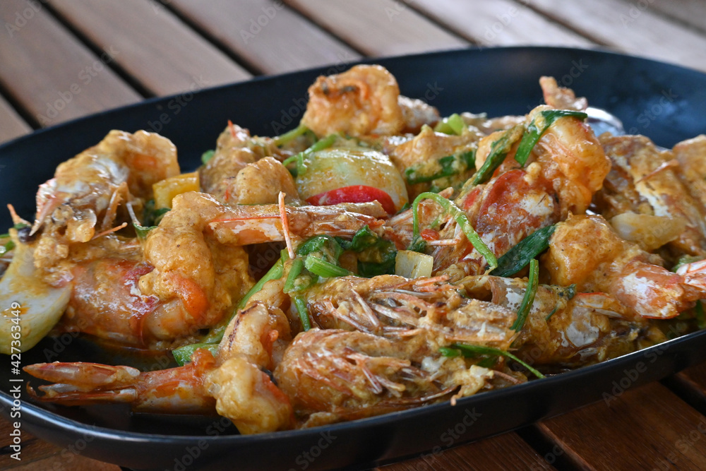 A Stir fried shrimp with curry powder on a vintage brown table in Thai restaurant. A Stir fried shrimp with curry powder on a vintage brown table in Thai restaurant.