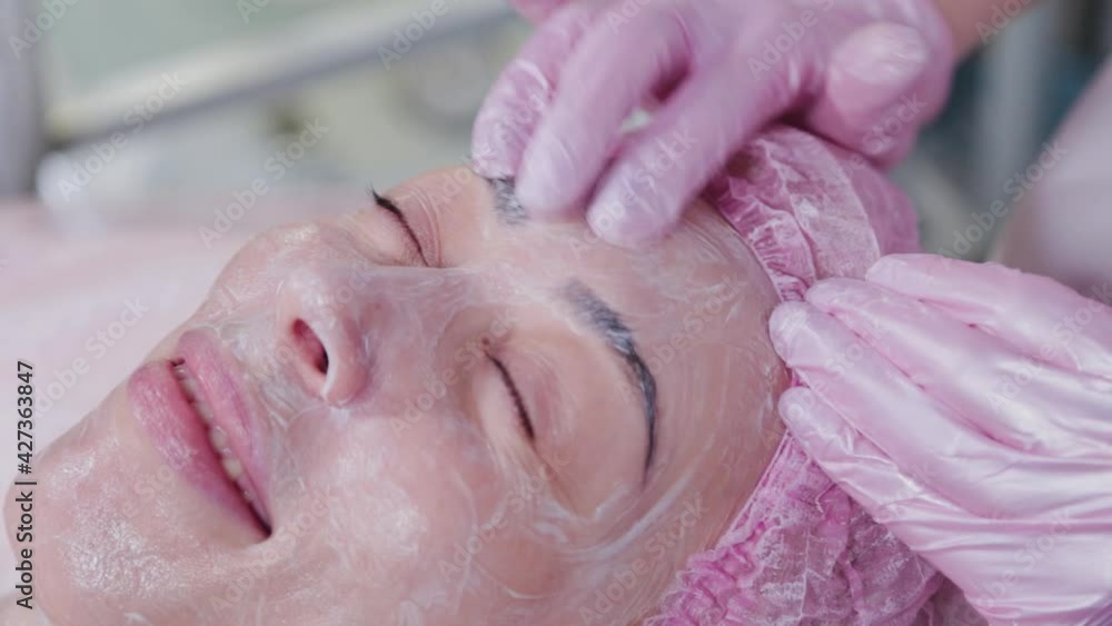 Woman beautician doing facial massage to young woman. Woman beautician doing facial massage to young woman.