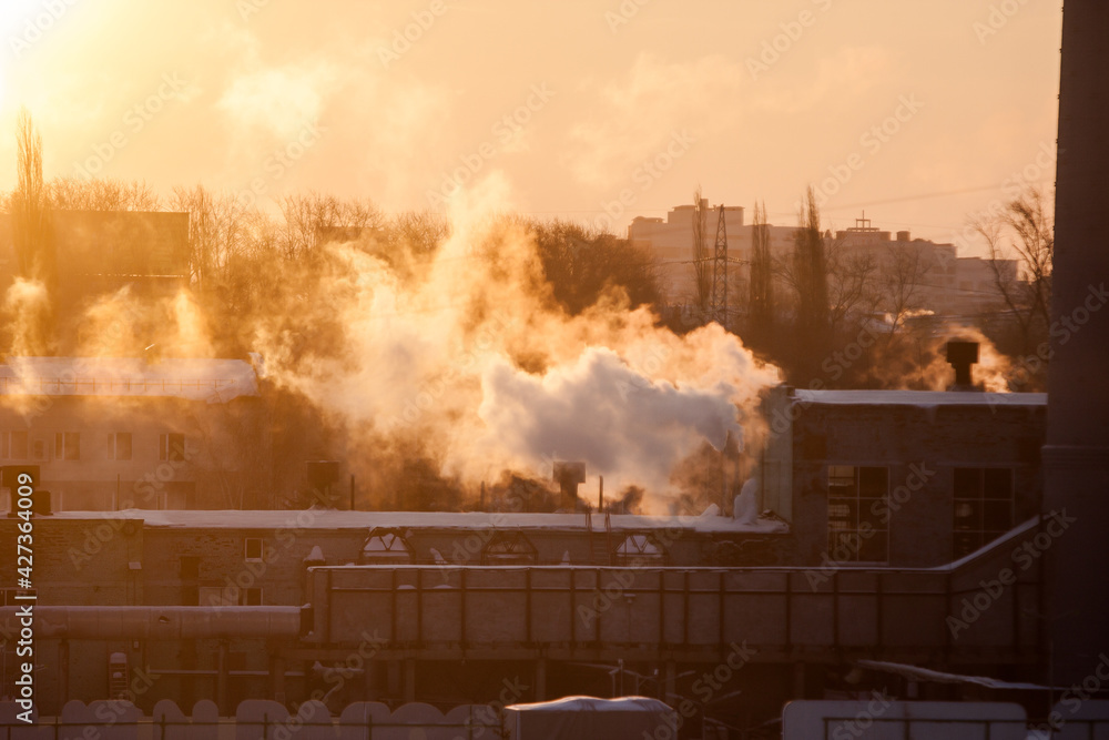 Obraz premium steam from the boiler room pipes in the contoured light of dawn, urban landscape