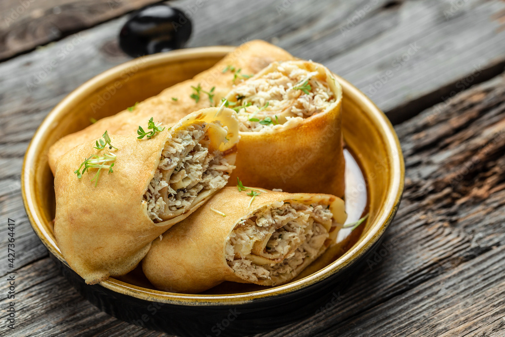 Savory crepe rolls with ground chicken meat. Pancakes with chicken on a wooden table, Long banner format, top view
