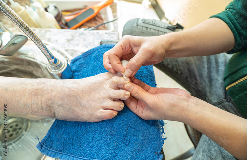 Pedicure process. Feet care. The master makes a pedicure on the foot of an elderly.
