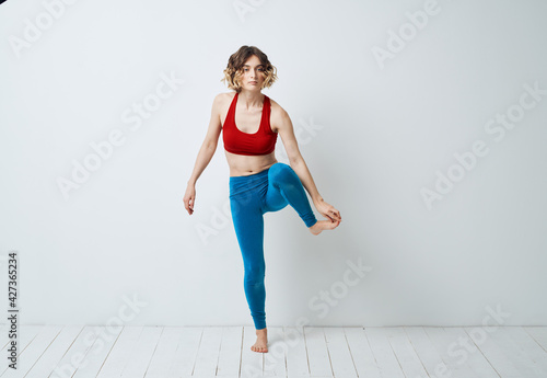 woman in blue leggings doing sports on a light floor indoors in full growth