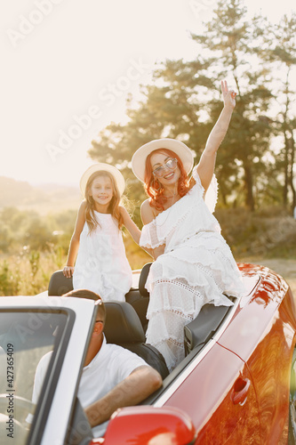 Family in a cabriolet convertible car at the sunset