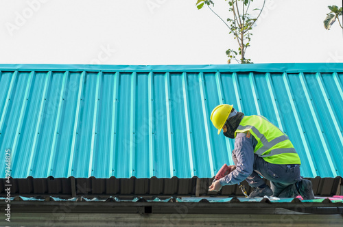 Roof constructionConstruction worker install new roof,Roofing tools,Electric drill used on new roofs with Metal Sheet. photo