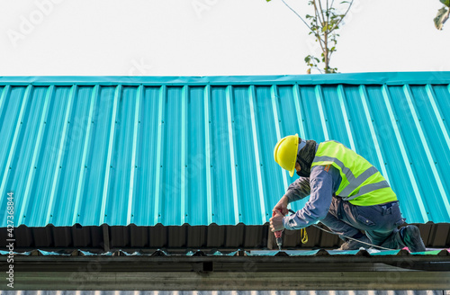 Roof constructionConstruction worker install new roof,Roofing tools,Electric drill used on new roofs with Metal Sheet.