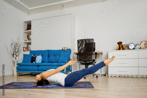 Woman does yoga at home in uttana padasana pose photo