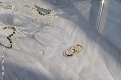 shadows from wedding glasses and wedding rings on a white background