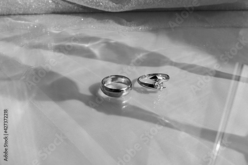 Wedding rings in the foreground with shadows from wine glasses
