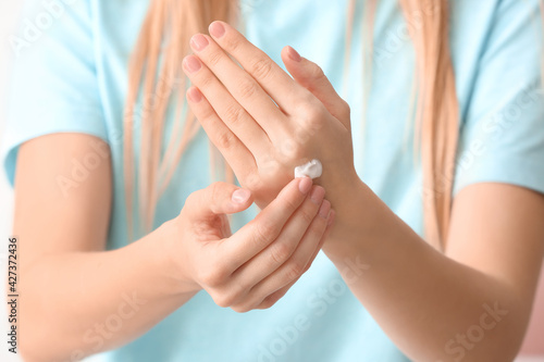 Young woman applying cream on her hands, closeup