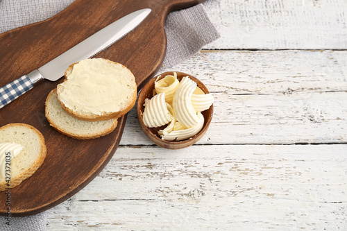 Bowl with fresh butter on light wooden background