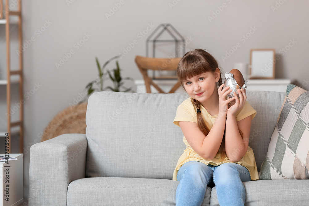 Fototapeta premium Cute little girl with chocolate Easter egg at home