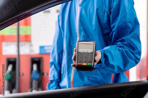 Service worker holding credit card reader for payment at gas station. Refuelling car and service payment with wireless bank payment terminal at gas pump photo