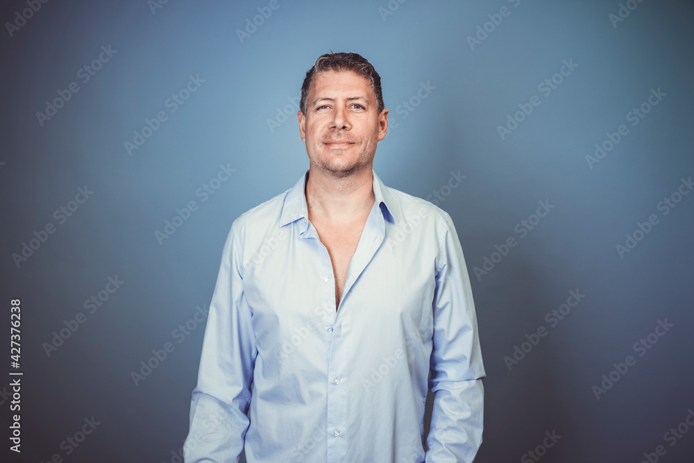 Fototapeta premium Middle aged business man with blue shirt posing against blue background in the studio