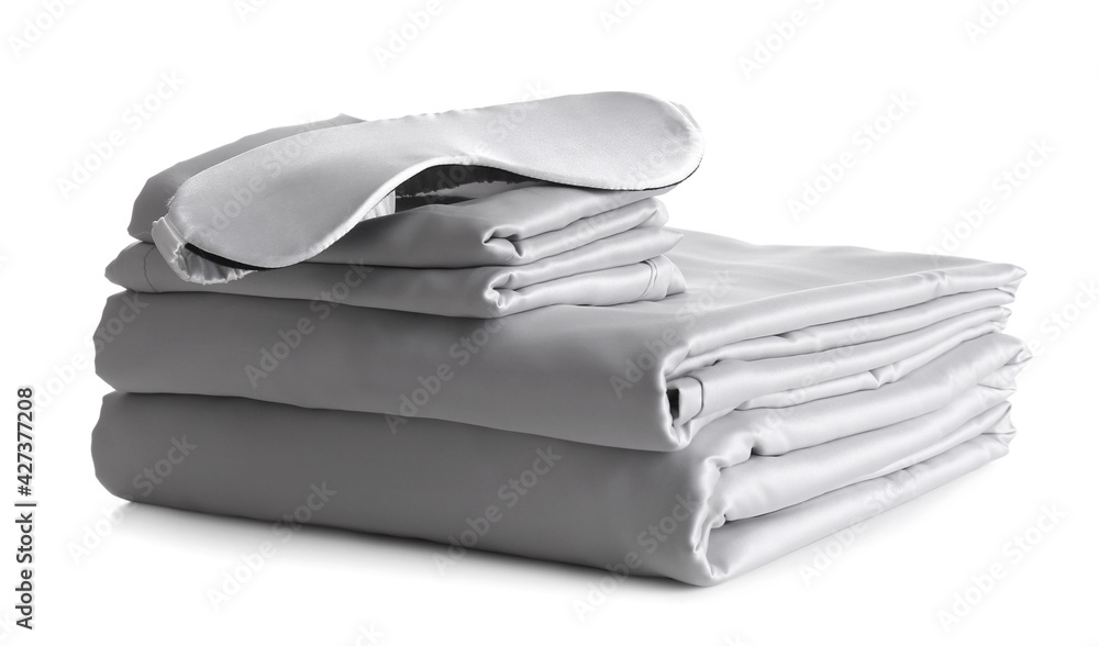 Stack of clean silky bed linen and sleeping mask isolated on white Stack of clean silky bed linen and sleeping mask isolated on white