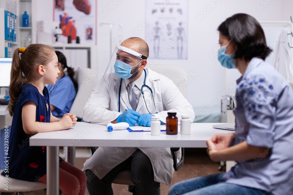 Medical doctor wearing face mask and visor writing prescription on clipboard against covid19. Practitioner specialist in medicine providing professional treatment services in hospital clinic. Medical doctor wearing face mask and visor writing prescription on clipboard against covid19. Practitioner specialist in medicine providing professional treatment services in hospital clinic.
