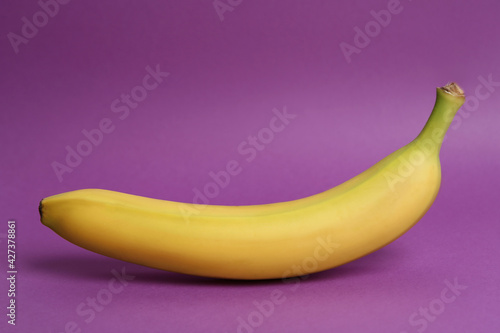 Ripe sweet yellow banana on purple background