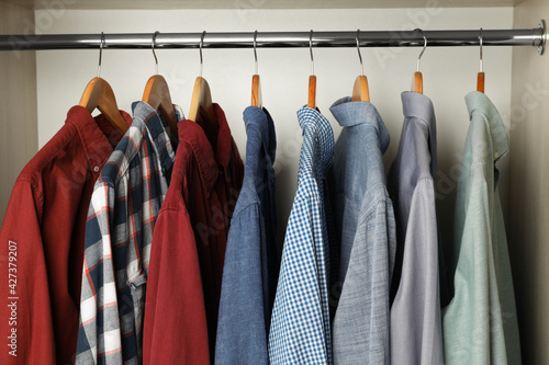 Hangers with clothes on rack in wardrobe
