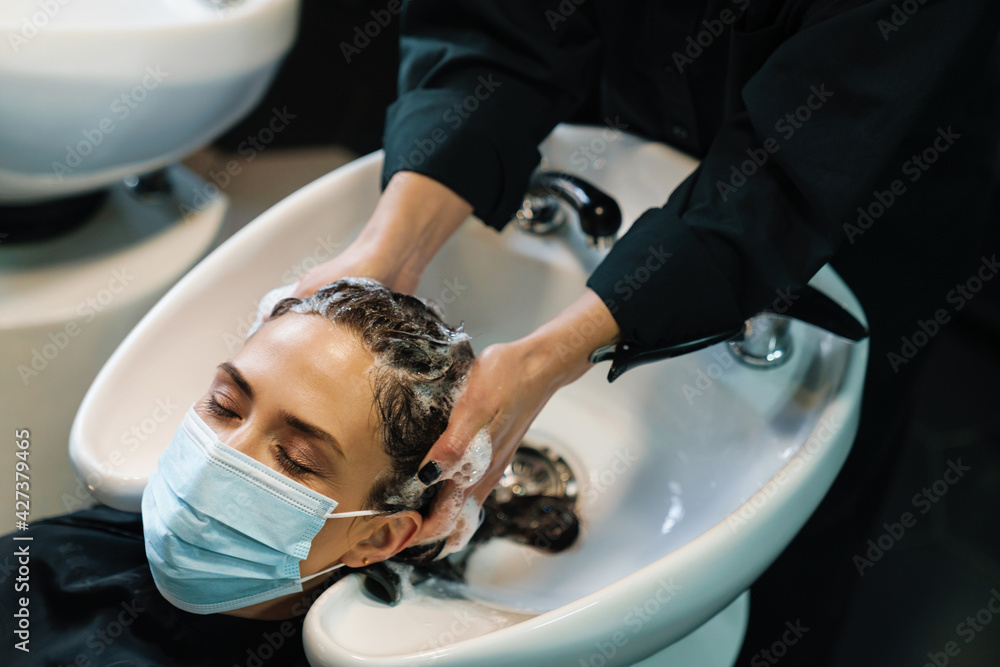 Woman washing her client's hair while doing hairstyle in beauty salon Woman washing her client's hair while doing hairstyle in beauty salon