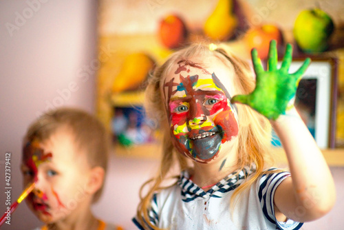 A happy child draws with colorful paints. Portrait of a child with a painted face. Happy childhood. selective focus