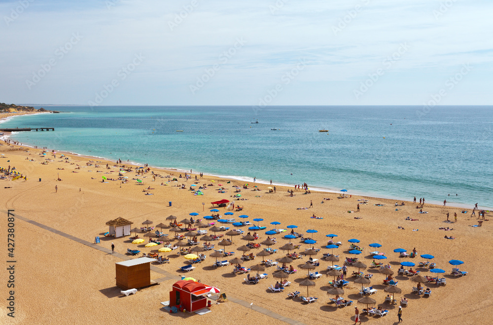Portugal. Algarve. People are relaxing on a sandy town beach by the sea in summer holidays. Seaside rest conception, top view Portugal. Algarve. People are relaxing on a sandy town beach by the sea in summer holidays. Seaside rest conception, top view