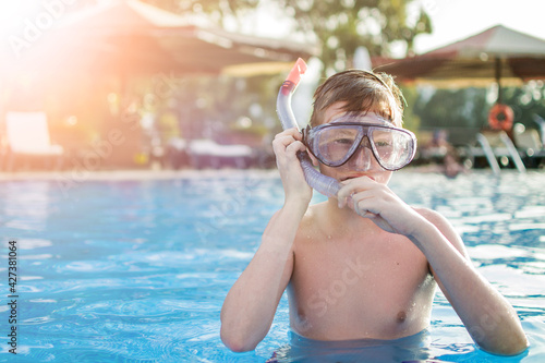 Teenager boy wearing mask swimming in the pool. Happy holiday concept. Cute happy little boy swimming and snorking in the swimming pool. photo