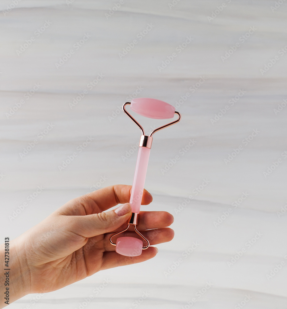 A woman's hand holds jade face roller. Face care at home, alternative medicine. Facial Massage Tool. Copy space. A woman's hand holds jade face roller. Face care at home, alternative medicine. Facial Massage Tool. Copy space.