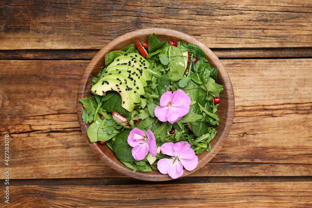Fresh spring salad with flowers on wooden table, top view Fresh spring salad with flowers on wooden table, top view