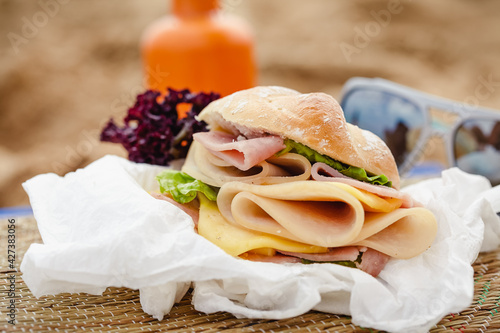 Fototapeta Naklejka Na Ścianę i Meble -  Sandwich with ham and cheese on a beach