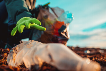 A worker in rubber gloes collects garbage on a sea beach. Hand close-up. The concept of Earth Day and ecology's problem. Bottom view