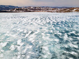 Melting ice on the lake in early spring. Aerial drone view of the lake and mountains. South Ural, Russia