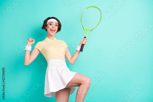 Photo of positive amazed excited young lady raise racket fist win match isolated on pastel teal color background © deagreez