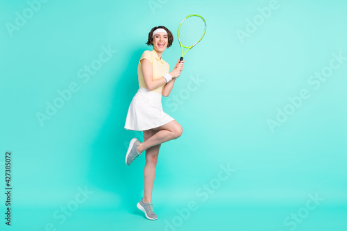 Full length body size view of lovely sportive cheerful girl playing tennis country club isolated over bright teal turquoise color background © deagreez