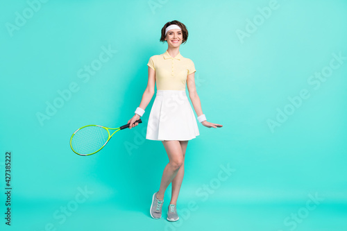 Full size photo of happy positive cheerful beautiful girl tennis player in sportswear hold racket isolated on teal color background