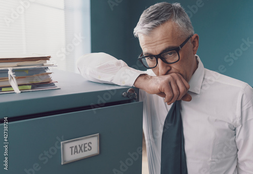 Pensive businessman leaning on a filing cabinet