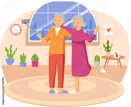Elderly couple standing with monopod against background of window and making photo together on phone