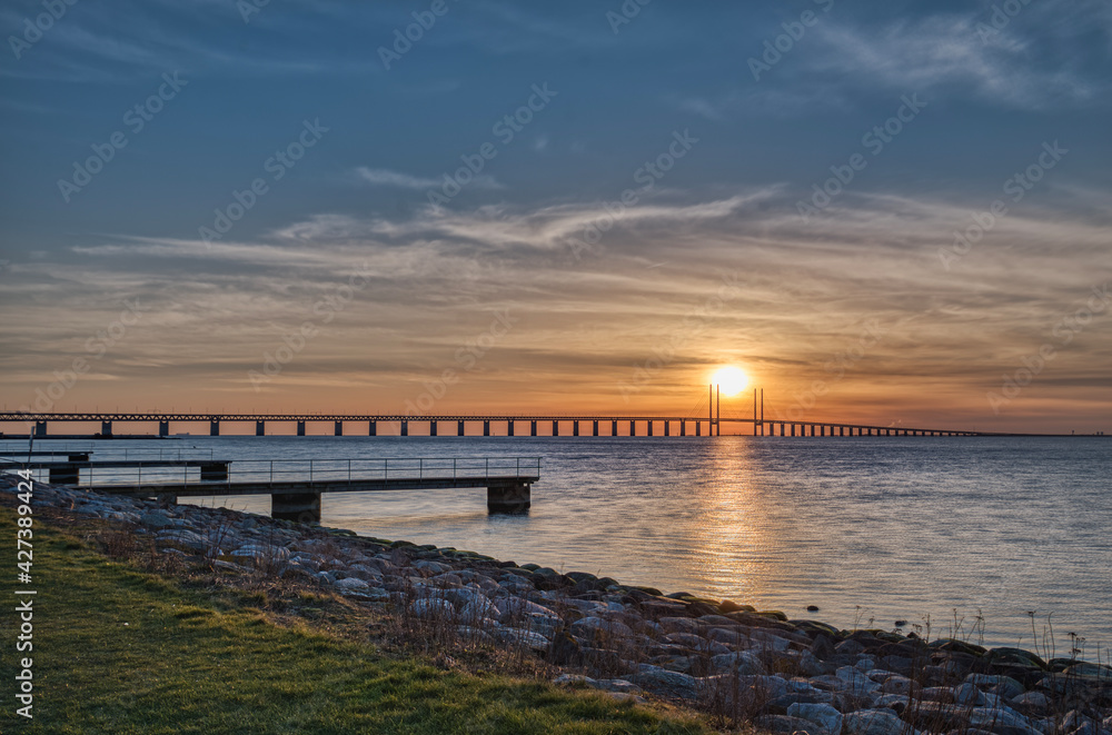 Sunset on the Oresund Bridge (Oresundsbron) in the Baltic Sea. The road rail overpass connects Malmo to Copenhagen across the Oresund Strait and border commuters or frontier workers cross it daily