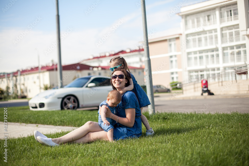 Fototapeta premium young mother with daughters are sitting on the grass