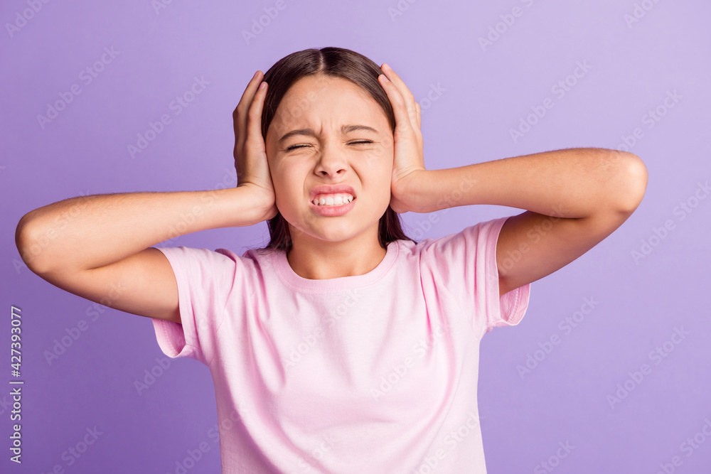 Photo of young girl unhappy unwell cover ears hand headache pain suffer isolated over purple color background Photo of young girl unhappy unwell cover ears hand headache pain suffer isolated over purple color background