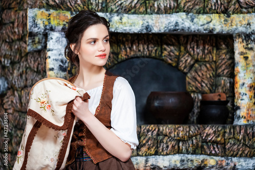 Portrait of Young Smiling Caucasian Brunette Woman Posing With Fancywork.Hoop in Retro Dress In Rural Environment. photo