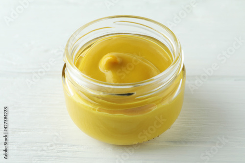 Glass jar with mustard on white wooden table