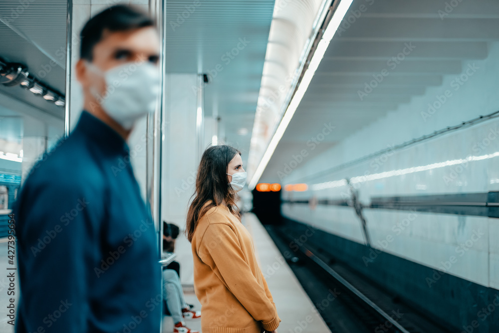 passengers in protective masks standing at the metro station