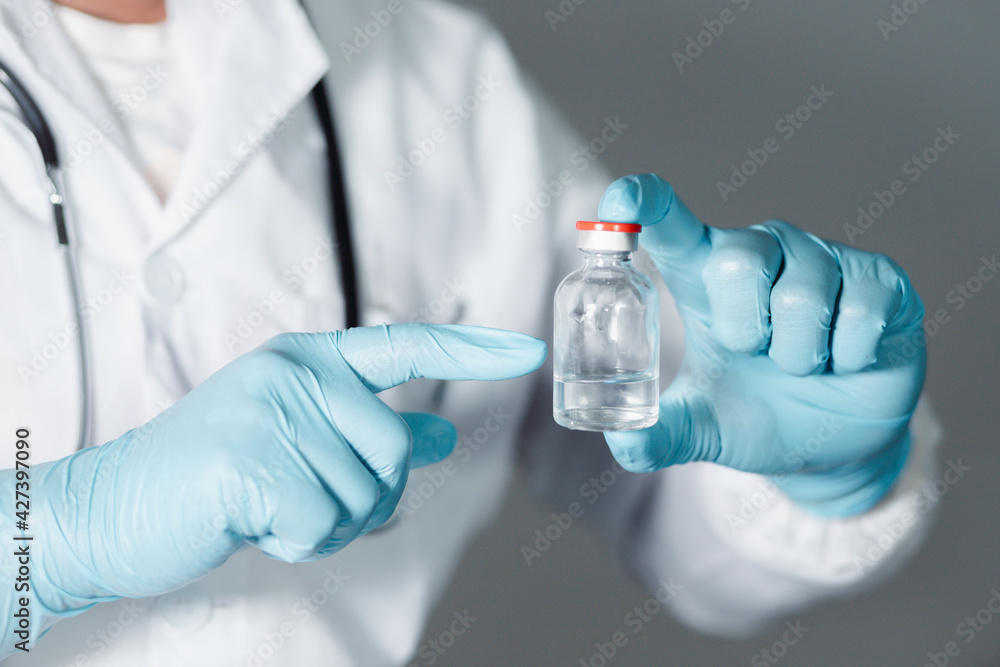 A doctor or scientist in a laboratory develops a medical vaccine. Holds a syringe with liquid vaccines to study and analyze antibody samples for new strain of COVID-19 patients in 2021.
