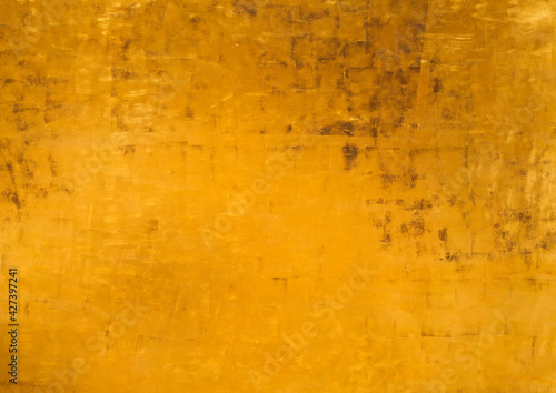 Vintage golden wall with matte paint texture with gilded effect, dark stains and scratches on surface.