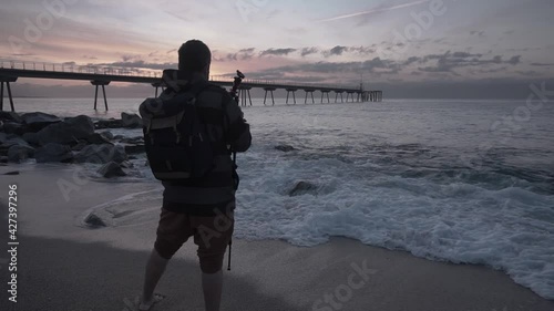 Photographer setting up tripod and camera equipment to take photos of the sunrise and landscape at the beach